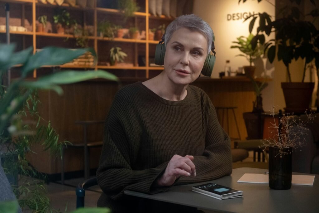 “Mulher lendo em uma sala com plantas ao redor.”