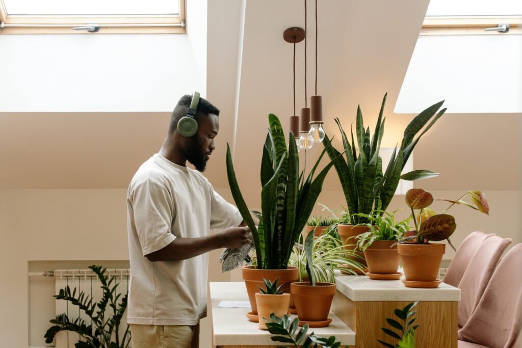 “Pessoa regando plantas em casa com sorriso no rosto.”